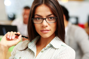 Portrait of a young thoughtful businesswoman in office, with her colleagues in background